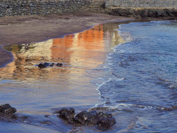 Spiegelung von Häusern am nassen Sandstrand